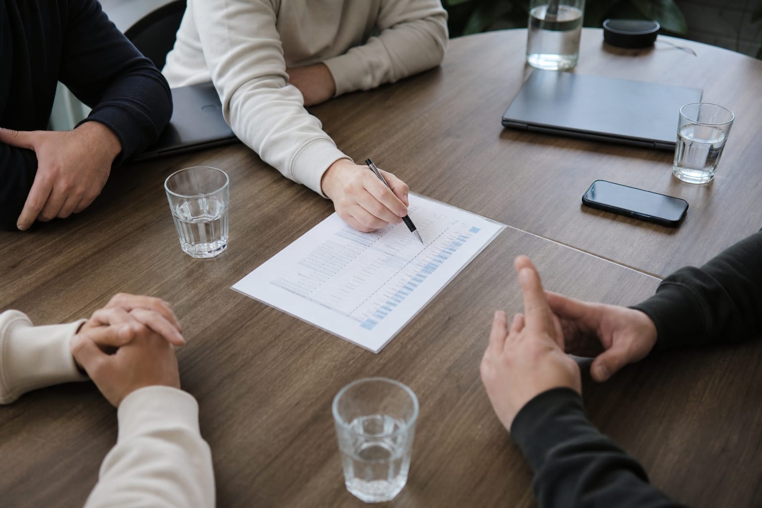 Hands reviewing a printed SEO report on a table, a pen circling one data row