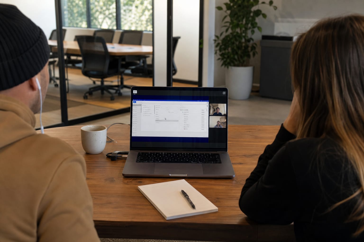 Two-person agency team on a video call reviewing a vendor demo dashboard with a question-filled notepad