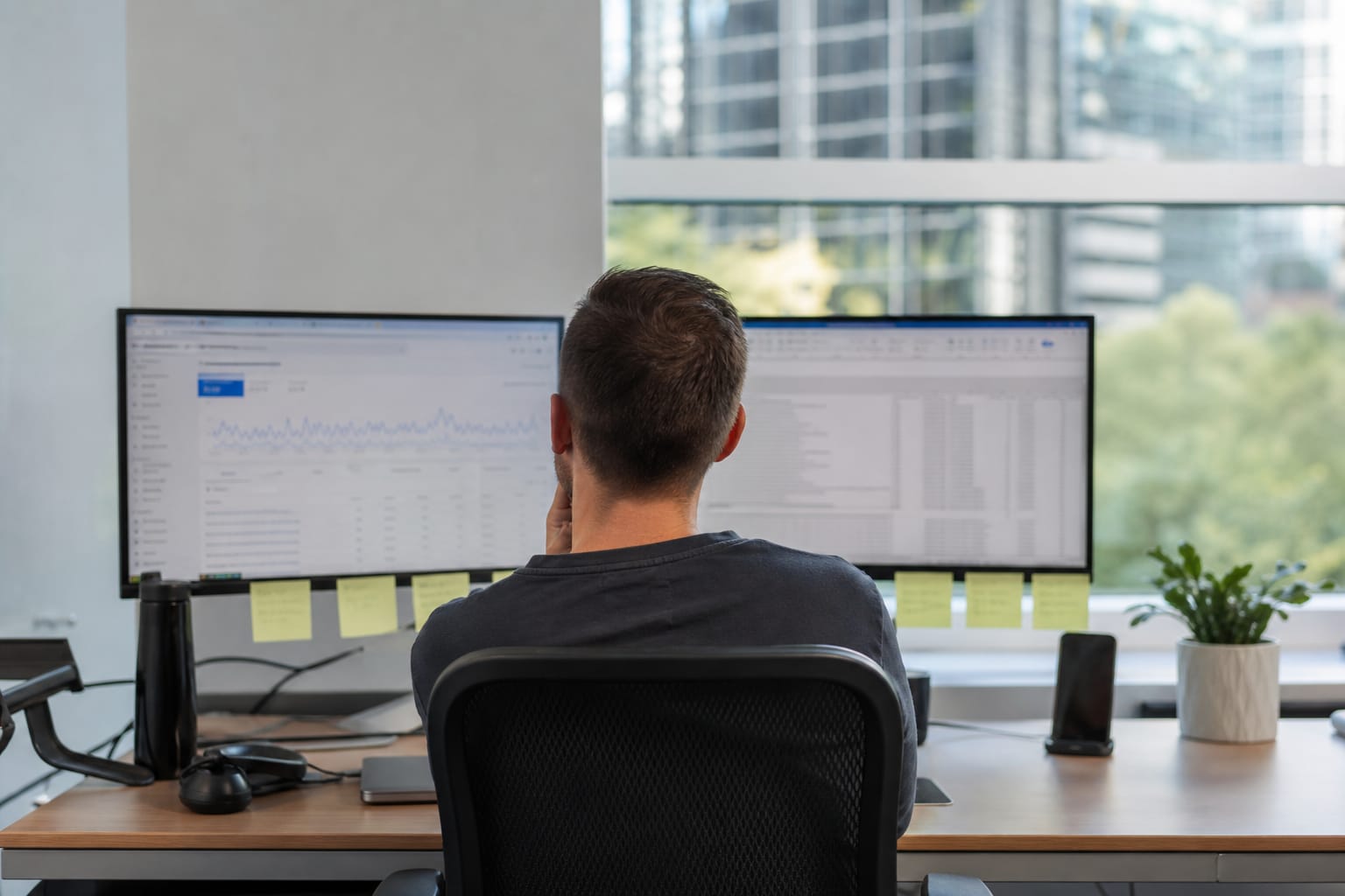 Analyst comparing a Search Console graph and a spreadsheet of URLs and citation dates on two monitors.