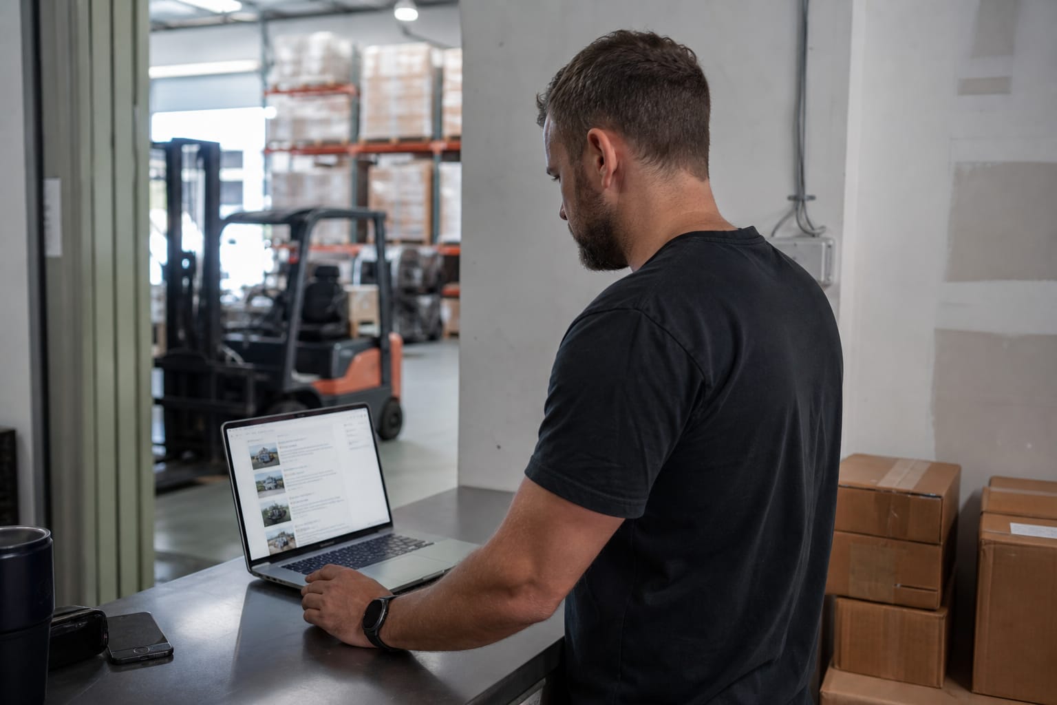 Moving company owner in a warehouse office viewing his business ranked in search results on a laptop.