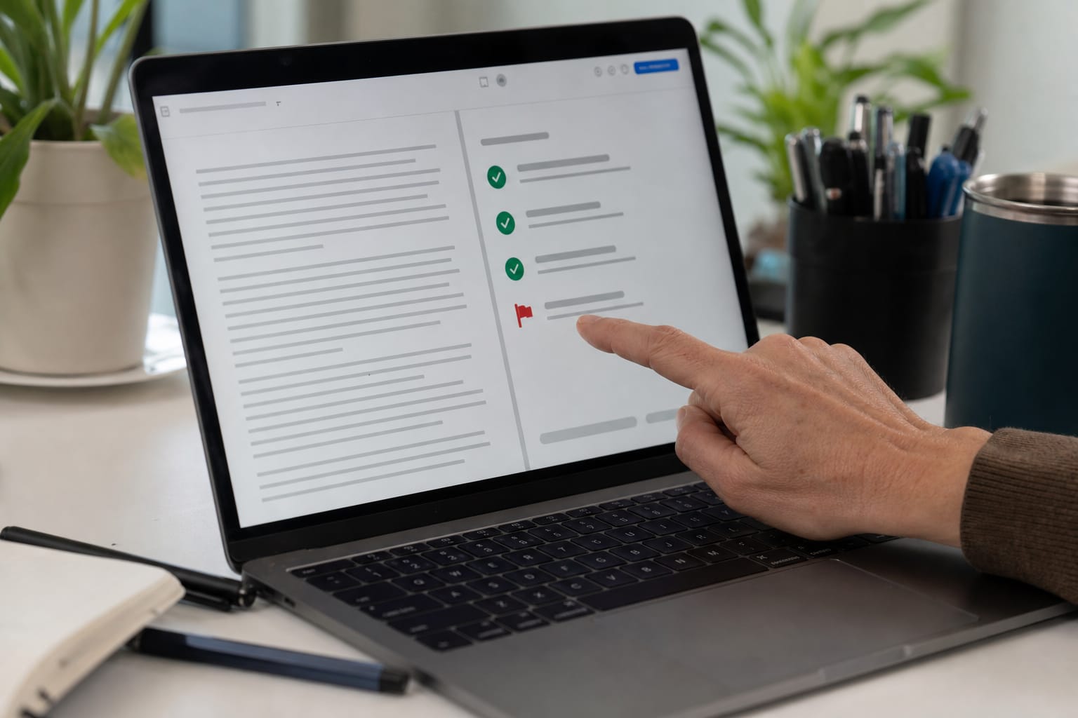 Laptop screen split between a draft article and a QA checklist with one item flagged red.