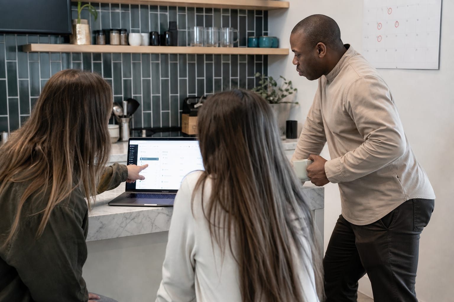 Three people around a laptop reviewing a CMS publishing screen in a casual office