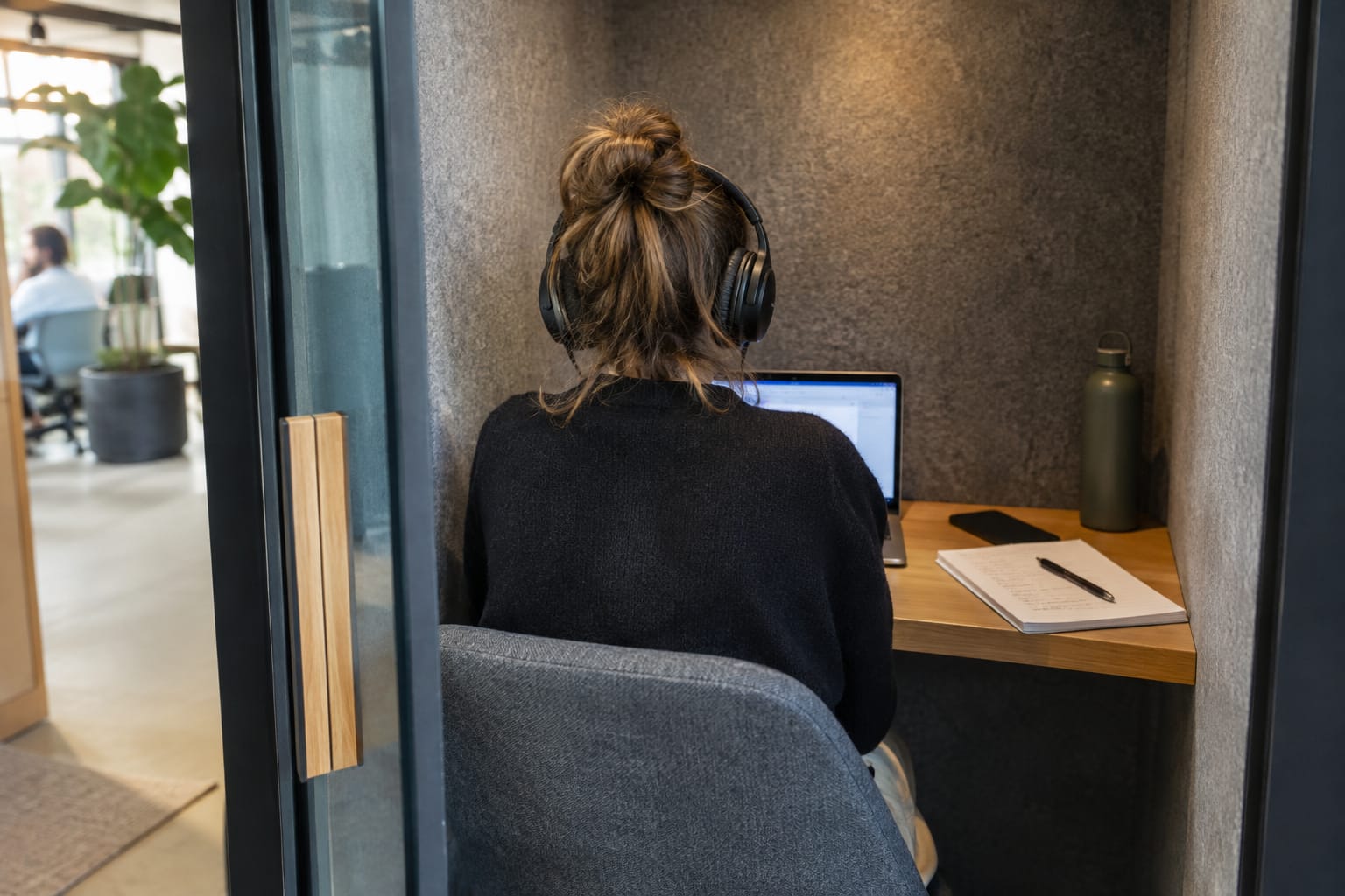 Account manager in headphones on a video call with a handwritten list of monthly deliverables on a notepad