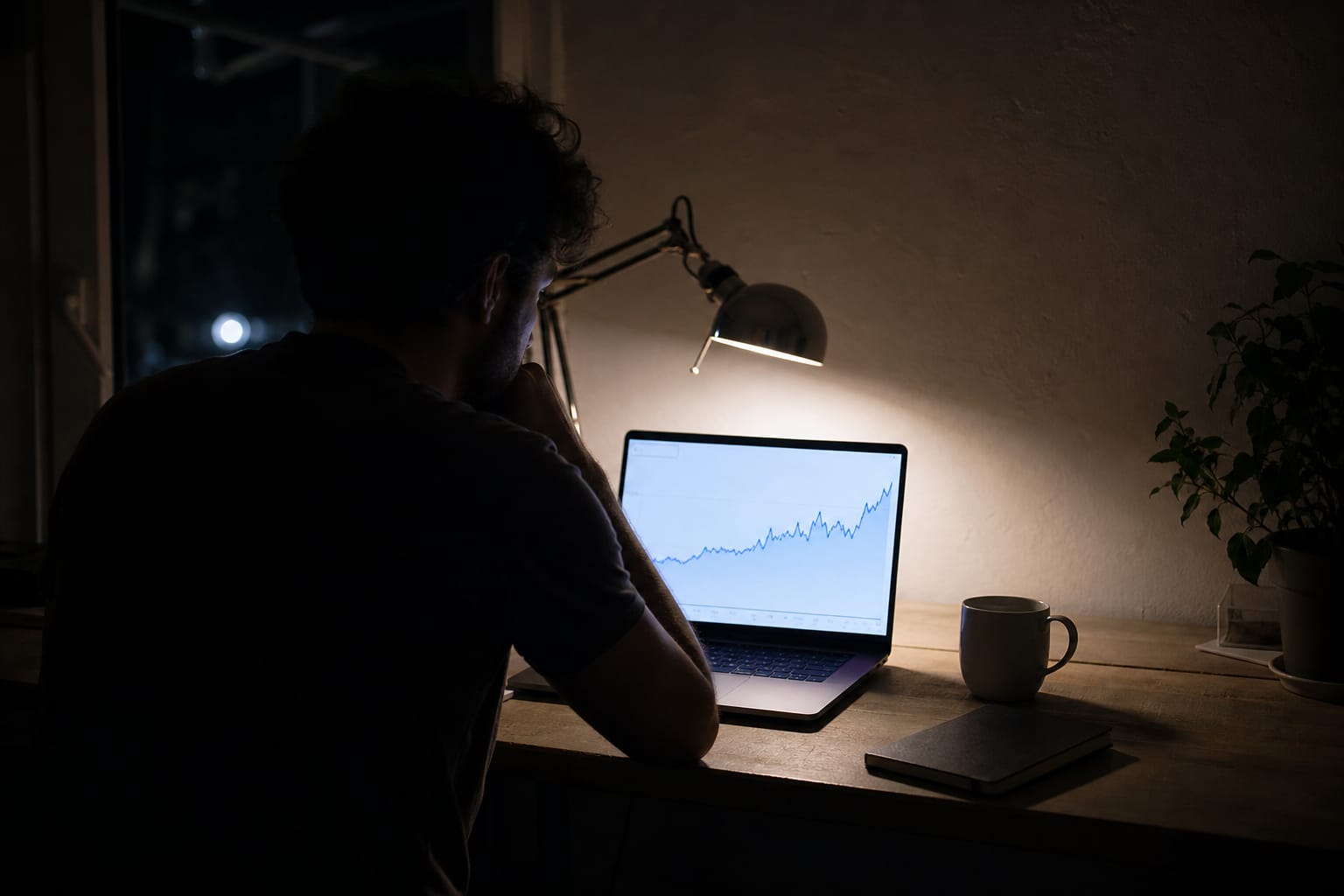 Founder at a home desk at night viewing a six-month upward organic traffic chart on a laptop.