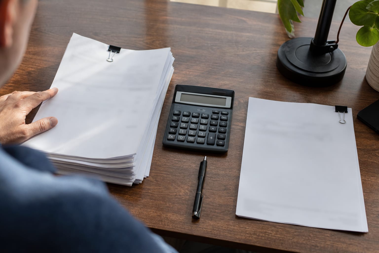 Two invoices on a desk: a multi-page agency retainer beside a single-line subscription receipt with a calculator.